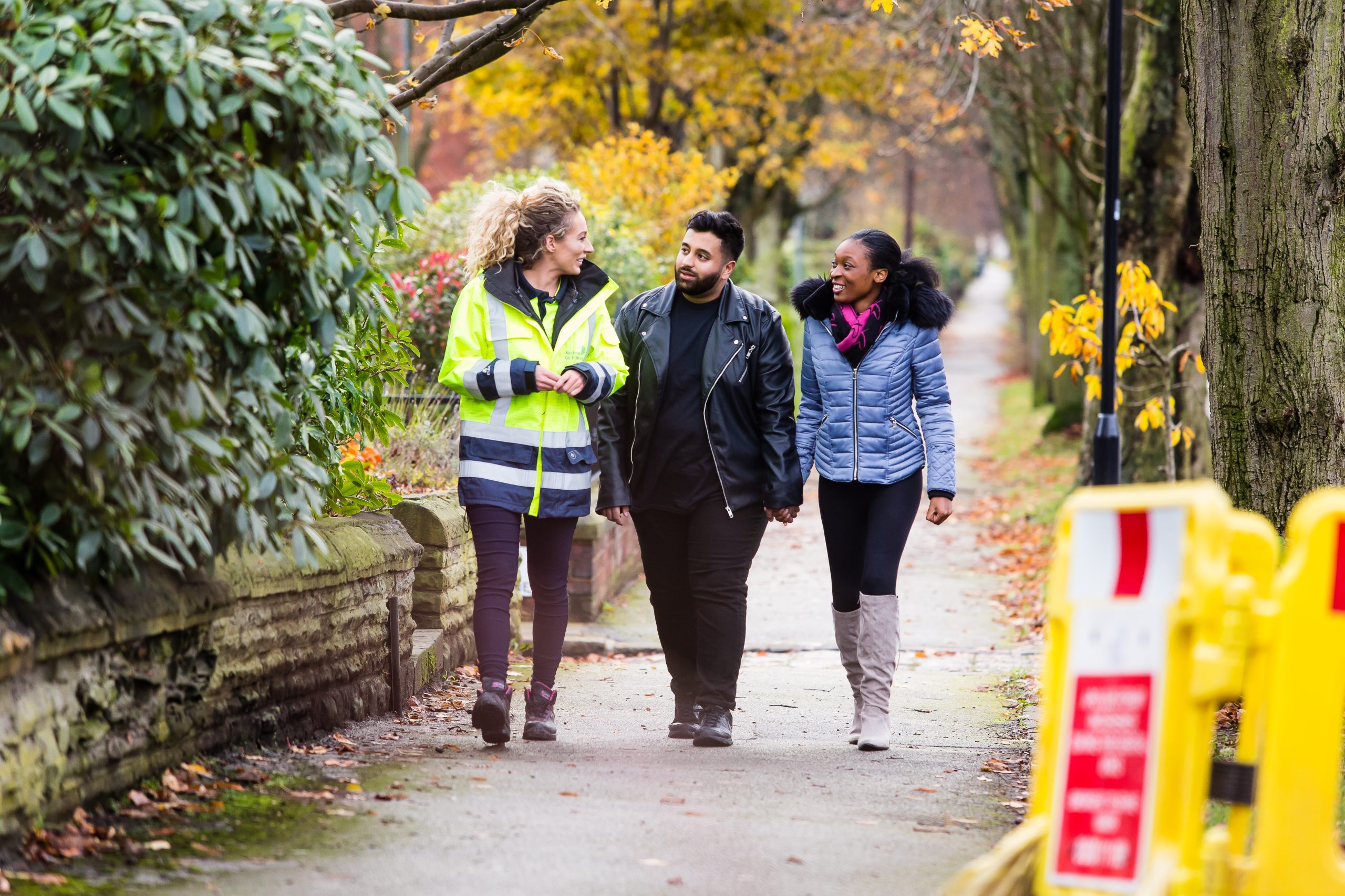 Image of Northern Gas worker in high vis next to two members of public walking down the street and talking