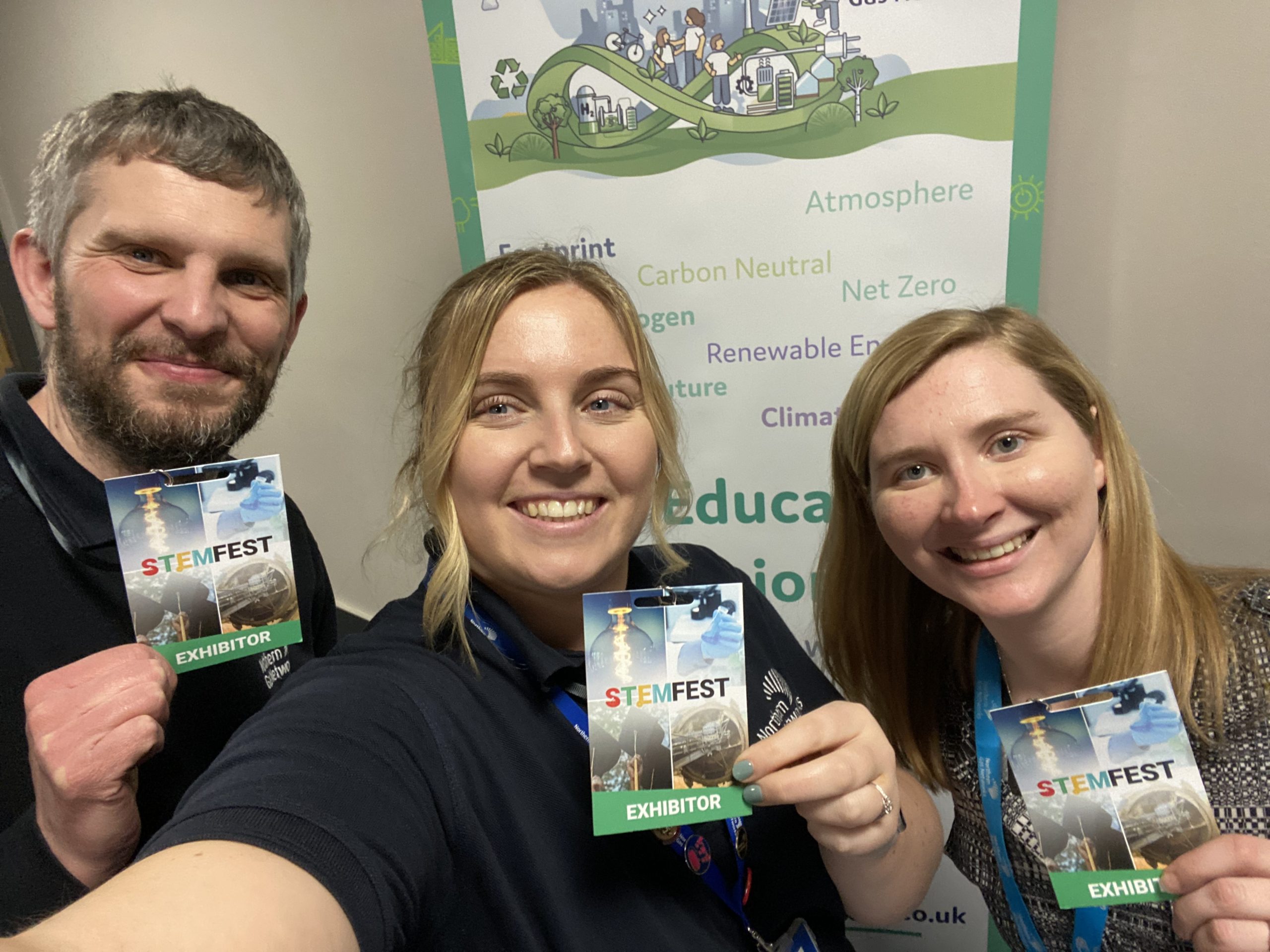 A team of three people (one man, two women) holding STEMFEST exhibitor badges